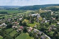 Aerial landscape view of village houses and distant green cultivated agricultural fields with growing crops on bright