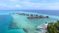 AERIAL: Luxury wooden overwater cabins are surrounded by the turquoise ocean.