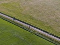 Aerial of meadowland separated by straight bicycle lane with cyclist on the dutch island of Texel