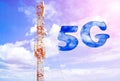 Aerial of mobile communication on a background of a blue cloudy sky. High antenna. Sun rays and glare. The inscription is 5G. Royalty Free Stock Photo