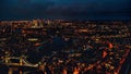 Aerial night view of west London with Tower Bridge over river Thames bottom left corner, illuminated buildings glowing in dark Royalty Free Stock Photo