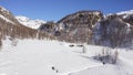 Aerial over winter wonderland, snowy mountain valley in sunny winter day.Winterland scene with lodges and people walking