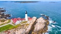 Aerial overlooking amazing Portland lighthouse in Maine with rocky coasts and crashing waves