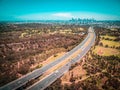 Aerial panorama of highway leading to Melbourne downtown skyscrapers on hot summer day.
