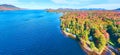Aerial panorama over blue lake in fall with endless forest and mountains in peak foliage Royalty Free Stock Photo