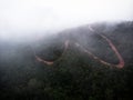 Aerial panorama of red mud dirt track road meandering through lush dense green cloudy tropical rainforest Amazonas Peru