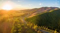 Aerial panorama of sunset over countryside - winding road, fores