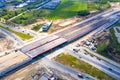 Aerial panorama top down view of an unfinished asphalt covered road with dirt, tracks of heavy machinery at construction site. The