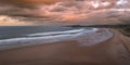 Aerial panorama view of Embleton Bay and Dunstanburgh Castle with dramatic sky at sunset