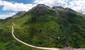 Aerial panorama view of the road for travelers on a motorcycle, car, incredible beauty views of green meadows and majestic