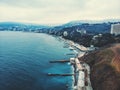 Aerial panorama of winter Yalta in cloudy day, embankment with breakwaters, old European city on Black Sea