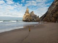 Aerial panorama of young male tourist in yellow jacket at Praia da Ursa atlantic coast cliff sand beach Lisbon Portugal