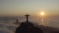 Aerial, panoramic footage of a statue of Christ the Redeemer over clouds in a morning sunlight