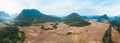 Aerial panoramic Muang Ngoi Laos river valley yellow ripe rice fields agriculture dramatic landscape scenic pinnacle cliff
