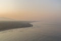 Aerial panoramic view of beautiful Murdeshwar beach on a foggy winter morning with orange and yellow shades in the sky at