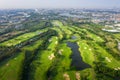 Aerial panoramic view drone shot of beautiful golf course with people playing golf in field and houses in city Royalty Free Stock Photo