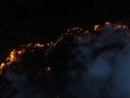 Aerial panoramic view of a forest fire at night, heavy smoke causes air pollution, and fire in full blaze. Natural