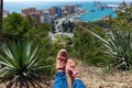 Aerial panoramic view of Malaga city, Andalusia, Spain in a beautiful summer day with the feet of a tourist in sport shoe sneaker