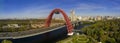 Aerial panoramic view on modern urban red cable arch bridge with automobiles, cars on road above the river, amont park Royalty Free Stock Photo