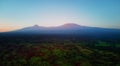 Aerial, panoramic view on Mount Kilimanjaro volcano, summit covered in snow lit by first sun rays with masai villages with Royalty Free Stock Photo