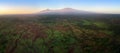 Aerial, panoramic view on Mount Kilimanjaro volcano, summit covered in snow lit by first sun rays with masai villages with Royalty Free Stock Photo