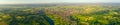 Aerial panoramic view of over green hilly landscape with small town