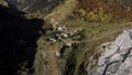 Aerial panoramic view of a small mountain village with old houses. Footage. Green and yellow autumn trees growing on one