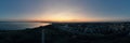 Aerial panoramic view of a to the coastline of the city with dramatic clouds sunset sky and views of the sea surface Royalty Free Stock Photo