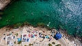 Aerial of people on vacation laying on towels on the beach and some swimming in the turquoise sea