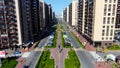 Aerial of people walking down the green alley in the summer city street. Motion. Flying along the road with buildings