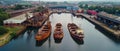 An aerial perspective of an industrial shipyard, showcasing rustic cargo ships docked by warehouses under an overcast Royalty Free Stock Photo