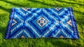 Aerial Perspective of Intricate Uzbek Ikat Adras Textile Embroidered on a Vibrant Emerald Meadow A Stunning Display of