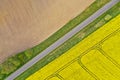 Aerial perspective view on rural landscape with yellow field of blooming rapeseed, diagonal line tractor tracks, plowed soil, Royalty Free Stock Photo