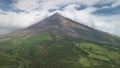 Aerial of Philippines volcano peak eruption clouds haze. Hiking path at hillside green grass valley Royalty Free Stock Photo