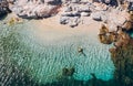 Aerial photo of man lying on the water in STAR pose on rocky pebbly beach and sun tanning. Soft waves washing his body on lonely Royalty Free Stock Photo