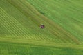 Aerial photo of meadow grass landscape and farmer in tractor mowing green grass field after the cut grass can dry and be picked up Royalty Free Stock Photo