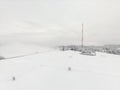 Aerial photo of radio and TV mast in front of wall of fog in snow on hillside Royalty Free Stock Photo