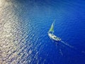 Aerial photo of a sailboat navigating through a tropical pass between reefs