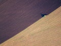 Aerial photo of a tractor ploughing a field in a countryside