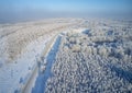 Aerial photo of winter road surrounded by birch forest.  Drone shot of trees covered with hoarfrost and snow Royalty Free Stock Photo