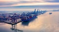 Aerial photograph of Felixstowe container port in the early morning autumn mist, a cargo ship being loaded, rows of stacked multi-