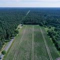 Aerial photograph of a rectangular, arable land between woods and a dead straight asphalted country road from greater height,