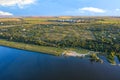 Aerial photography, the river bank against the background of sunset summer sunbeams, steppe trees and a working village in the