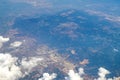 Aerial photography. View from the plane window: flying above the clouds, below you can see mountains and green fields. Royalty Free Stock Photo