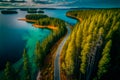 Aerial picture of a road along the coast in summertime with lush forests and clear lakes.