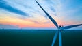 Aerial pink and orange sunset with blue clouds over wind farm with close up of turbine Royalty Free Stock Photo