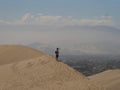 Aerial postcard panorama view of isolated lonely single man person tourist dry sand dune desert of Huacachina Ica Peru