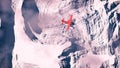 Aerial of red airplane flying over arctic snow landscape.