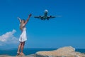 Aerial Rendezvous: Girl in White Dress on Stones, Plane Above the Blue Sea Royalty Free Stock Photo