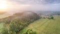 Aerial of Riserva Naturale della Marcigliana, tree lines, green meadow, foggy sunset background